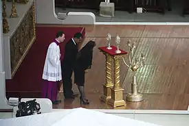 Le candélabre à sept branches et les deux reliquaires devant lesquels s'inclinent la miraculée Floribeth Mora Diaz et son mari, Edwin Antonio Arce Abarca