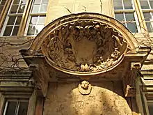 un grand coquillage  avec un bouclier au centre et des feuilles sculptées autour ; une tête de chérubin sous le coquillage