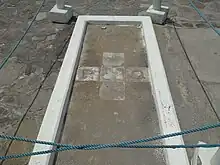 Tombe rectangulaire plane avec 5 pierres carrées formant une croix au sol. La pierre de gauche est gravée de la lettre P (Philip) et la pierre de gauche de la lettre Q (Quaque)