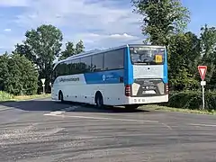 Un autocar blanc et bleue partant en direction de la gauche de l'image.
