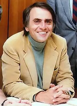 Photo en couleur. Homme assis portant un veston et souriant.