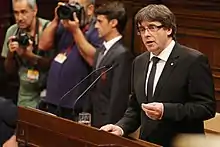 Carles Puigdemont prenant la parole sur les résultats du référendum derrière un pupitre.