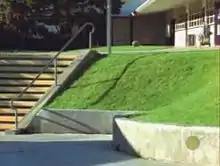 Photo du Carlsbad gap à l'école de Carlsbad, prise depuis le bas, où l'on voit à côté de l'escalier, la partie herbeuse par-dessus laquelle il faut sauter depuis l'esplanade située plus haut.