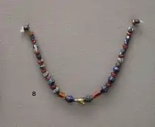 Collier en perles de cornaline et lapis lazuli, amulette en or en forme de mouche, provenant des tombes royales d'Ur. British Museum.