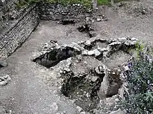 Groupe de tombes remblayées à côté d'un mur en ruines