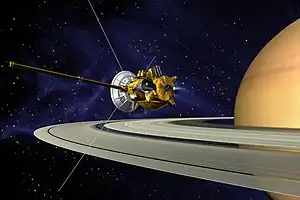 La sonde est montrée très proche des anneaux de Saturne, constituées d'une partie blanche et d'une partie dorée.