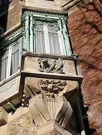 Photo en couleur d'une fenêtre en saillie sur de la pierre sculptée et entourée de quelques arabesques en métal