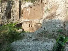 Façade d'une tombe creusée dans la falaise avec une fausse porte en forme de T gravée dessus.