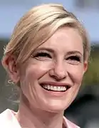 Photographie couleurs au format portrait d'une femme blonde au large sourire.
