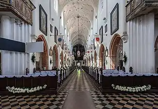 Photographie couleur d'une longue nef d'église entièrement blanchie et de style baroque.