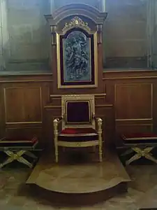 Cathèdre (fin du XVIIIe siècle) en bois doré et les deux tabourets assortis, avec derrière un panneau représentant le Christ revenant dans la gloire sur le cadre du lambris mouluré chêne et doré et deux consoles sur les côtés du panneau et à agrafe à coquille et rubans en haut.
