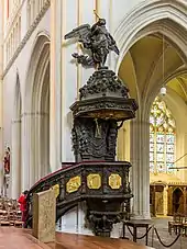 Photographie d'une chaire à prêcher en bois ornée de panneaux sculptés dorés