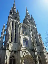 Façade ouest avec ses tours flanquées de baies géminées en plein cintre aux fenêtres entrecroisées de meneaux tréflés horizontaux, et surmontées d'une tribune.