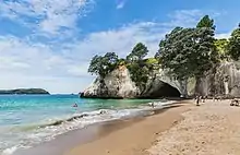 Une arche de rocher dans une falise blancge au-dessus de la mer.