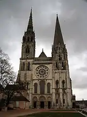 Photographie en couleurs de la façade d'une cathédrale gothique, sur fond de ciel plombé