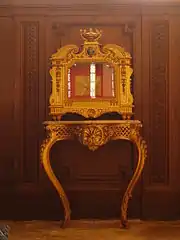 Reliquaire doré doté d'une vitre et posé sur une console de bois doré.