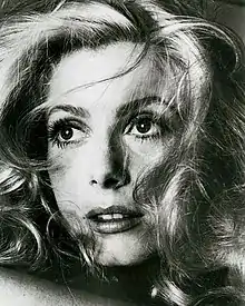 Photographie en noir et blanc du visage d'une jeune femme blonde aux traits fins et à la chevelure ébouriffée.