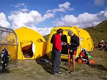 Deux tentes igloo de couleur jaune, sur un col montagneux.