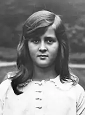 Photographie noir et blanc d'une petite fille à la mine triste portant des cheveux longs et clairs.