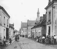 Photographie en noir et blanc du centre-ville d'une commune et ses habitants.