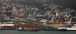 Photographie aérienne d'un port d'une grande ville, avec un stade au premier plan.