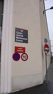 Plaque « Centre Activité Maintenance Central » placée à côté de l'entrée d'un bâtiment industriel.