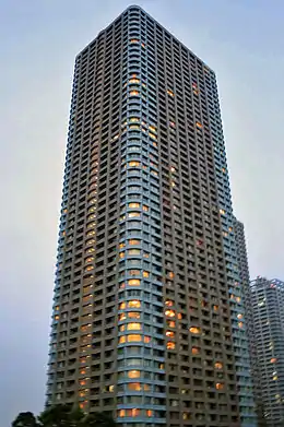 Ground-level view of an orange and white, rectangular, window-dotted high-rise