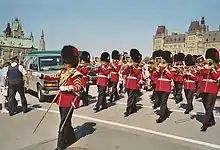Photo en couleur d'une fanfare militaire habillée en rouge jouant sur une place