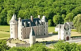 Photographie aérienne en couleurs d'un château avec des tours cylindriques et une enceinte basse qui le protège.