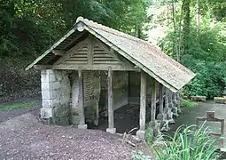 Photographie en couleurs d'un petit hangar au bord d'un ruisseau.