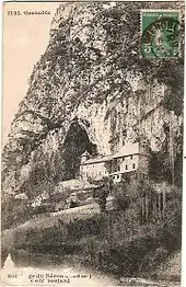 Carte postale ancienne avec un château au pied d'une montagne, au creux d'une grotte.