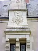 Photographie en couleurs d'un blason en bas-relief sur un mur.