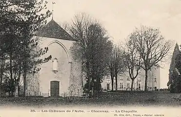 Carte postale ancienne en noir et blanc montrant une chaepelle de taille modeste au premier plan avec un château renaissance en fond de plan.