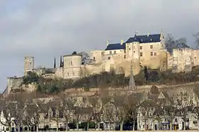 Photographie d'un château aux murs blancs au sommet d'une colline avec une ville en contrebas