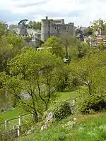 Vue des ruines du château à l'horizon, devant la ville de Clisson et derrière la végétation du parc.