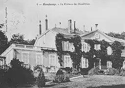 Photo noir et blanc montrant un manoir de style Napoléon III avec un fronton, un balcon, une terrasse à l'étage et de nombreuses cheminées.