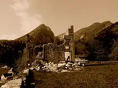 Image sépia des ruines d'un château avec des montagnes en arrière-plan.
