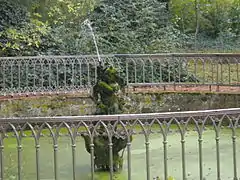 Vue d'une statue faisant office de jet d'eau, au centre d'un bassin.