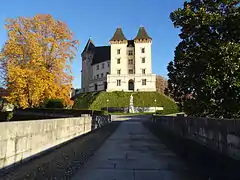 Photographie en couleurs représentant un château dans la perspective d'une longue allée.