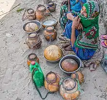 Photo de deux femmes assises par terre devant des vases remplis de lait