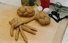 L’image présente un pain en cours de tressage, et deux pains tressés, avant leur cuisson.