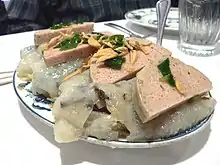 Tranches de chả lụa servi sur du bánh cuốn, et garni avec des échalotes.