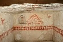 Vue d'une pièce souterraine munie de fresques peintes en rouge