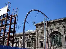 Photo montrant un échafaudage et un arc qui formera une partie de la structure de la verrière, devant la façade historique.