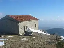 Un édifice religieux vu de dos, avec des montagnes et le ciel en arrière-plan.