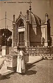 Photographie ancienne avec un ecclésiastique devant un bâtiment religieux.