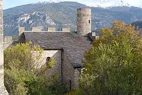 Bâtiment en pierre au toit en ardoise. Une tour dépasse de l'extrémité droite du toit.