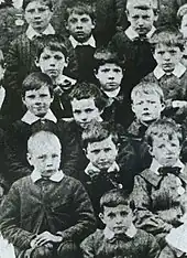 Photo en noir et blanc de plusieurs enfants en uniformes regardant l'objectif.