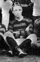 Portrait noir et blanc de Charles Newman avec le maillot de Newport. Il est assis par terre en tailleur avec les jambes et les bras croisés