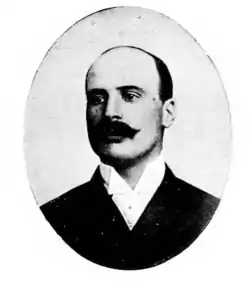 Portrait en noir et blanc d'un homme dégarni et portant une moustache.